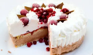 Torta gelato a strati con panna montata, frutti rossi e cioccolato. Una fetta è stata tagliata, rivelando il suo interno goloso.