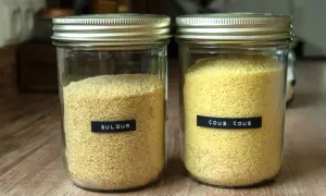 Zwei Gläser mit Getreide: links Bulgur, rechts Couscous. Beide sind gut sichtbar und bereit für die Zubereitung.