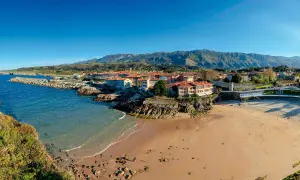 Costa asturiana con playa, pueblo costero y montañas. Descubre qué ver en Nueva de Llanes, un paraíso natural.