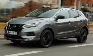 Szary Nissan Qashqai 2019 z czarnymi felgami pędzi ulicą, otoczony jesienną scenerią.