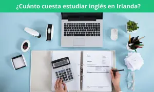 Calculadora, portátil y facturas sobre escritorio azul. Planificando el coste de aprender inglés en Irlanda.