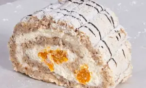 En bit Budapest bakelse med vispgrädde och aprikoser, pudrad med florsocker och dekorerad med choklad.