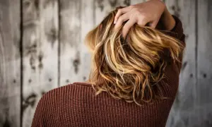 Capelli biondi mossi, una mano li accarezza. La vitamina C capelli dona lucentezza e forza.