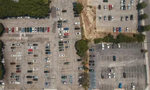 Widok z lotu ptaka na parking, gdzie doszło do kolizji na terenie prywatnym. Widać wiele zaparkowanych samochodów.