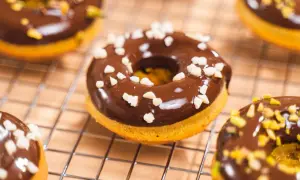 Deliciosos donuts de calabaza cubiertos de chocolate y trocitos crujientes.