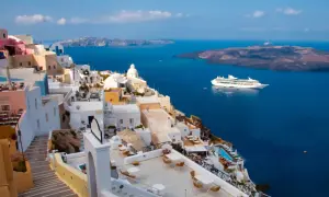 Santorini, Grecja. Białe domy na klifie, błękitne morze i statek wycieczkowy. Planujesz podróż? Pamiętaj o podatku turystycznym Grecja.