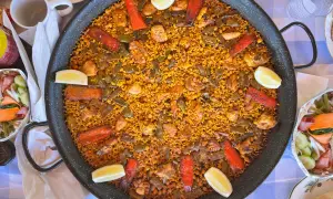 Paella gigante con pollo, judías verdes, pimientos rojos y limón. Los ingredientes paella lucen deliciosos en este plato tradicional español.