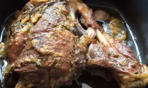 Un succulento agnello al forno, dorato e profumato con rosmarino e aglio, pronto per essere gustato.