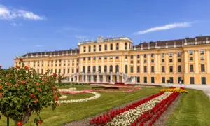 Wiedeń atrakcje: Pałac Schönbrunn z barwnymi rabatami kwiatowymi i zielonymi trawnikami.