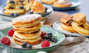 Fluffige Buttermilch Pancakes, bestäubt mit Puderzucker und garniert mit frischen Beeren. Ein Genuss für jeden Morgen!