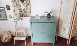 Metamorfoza komody Malm w miętowym kolorze, ozdobiona złotymi uchwytami. Obok wazon z kwiatami i kostki z napisami "Enjoy Life".