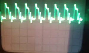 Zielone, kwadratowe fale na ekranie oscyloskopu, przypominające schodki.