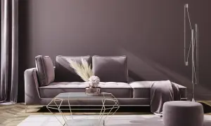 Ein luxuriöses Wohnzimmer in zarter mauve farbe mit einem Samtsofa, einem geometrischen Couchtisch und einem Hocker.