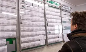 Mężczyzna przegląda tablicę z ogłoszeniami o pracę w urzędzie. Wiele ofert, w tym ten **bon zasiedleniowy**, czeka na chętnych.