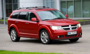 Czerwony Dodge Journey 3.6 z relingami dachowymi jedzie po brukowanej drodze.