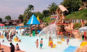 En livlig dag på Aqualandia Benidorm med folk som njuter av vattenrutschkanor och pooler under en solig himmel.