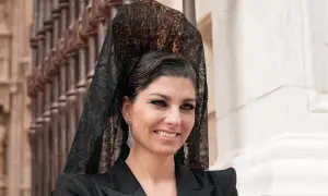 Mujer con peinado boda gitana, velo de encaje negro y pendientes largos. Sonríe con elegancia.