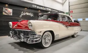 En skinande röd och vit Ford 56 cabriolet står i ett garage.