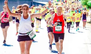 Uśmiechnięci biegacze na maratonie, radość i determinacja. Jak przygotować się do maratonu? Warto czerpać inspirację z ich pozytywnej energii!