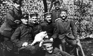 Grupp soldater i uniform, en håller en vit hund. En av männen liknar en ung Hitler.
