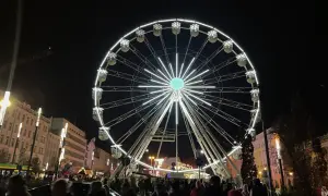 Nocny plac wolności poznań rozświetla ogromne koło widokowe. Tłumy ludzi spacerują wśród świątecznych iluminacji.