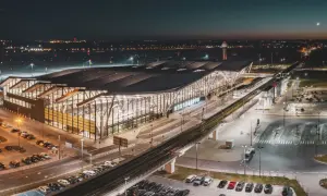 Nowoczesny terminal lotniska w Gdańsku nocą. Widok z góry pokazuje parkingi, drogi i tory kolejowe, ułatwiając planowanie, jak dojechać na lotnisko w Gdańsku.