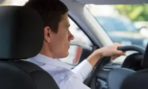 Uomo al volante, con la mano sul volante. Si può guidare una macchina intestata ad un familiare, anche se non è la sua.