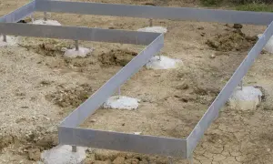 Metallrahmen auf Betonfundamenten für ein neues Haus. Das punkt fundament ist vorbereitet.