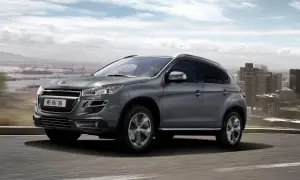 Szary Peugeot 4008 jedzie po drodze z widokiem na miasto i port.
