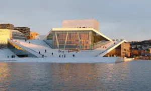 Oslo Winter: Menschen spazieren auf dem Dach der Oper, die im warmen Abendlicht glänzt.