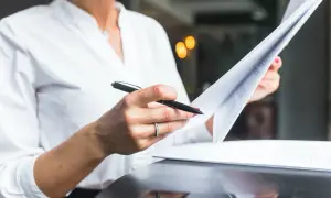 Kobieta w białej koszuli przegląda dokumenty, zastanawiając się, ile jest ważny odpis aktu małżeństwa.