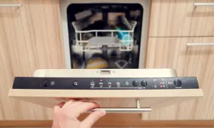 Hand öffnet Spülmaschine. Aquastop entblocken ist hier kein Thema, da die Maschine bereit für ein neues Programm ist.
