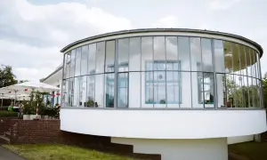 Ein modernes Gebäude mit runden Glasfronten, das an einen Aussichtsturm erinnert. Hier finden sich sicher einige Geheimtipps Dessau.