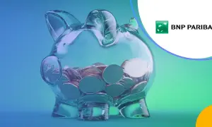 Przezroczysta skarbonka w kształcie świnki wypełniona monetami, logo BNP Paribas.