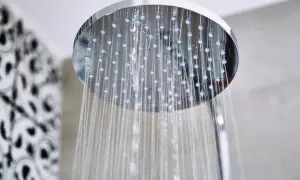 Acqua che scorre da un soffione doccia moderno, un promemoria per sapere come pulire il soffione della doccia per un getto perfetto.