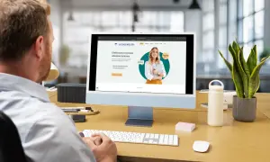 Mężczyzna pracuje przy komputerze, na ekranie którego widoczna jest strona internetowa z rankingiem agentów ubezpieczeniowych.