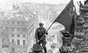 Soldat hisst Flagge über zerstörter Stadt. Berlin, 8. Mai Feiertag.