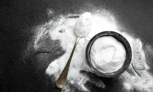 Un cucchiaio e una ciotola pieni di carbonato di sodio, mostrando i suoi molteplici usi in cucina e per la pulizia.