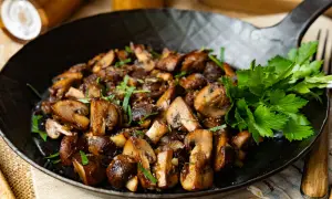 Gebratene Champignons in einer Pfanne, garniert mit Petersilie. Köstlich und einfach zuzubereiten.