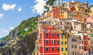 Färgstarka hus klättrar uppför en brant sluttning vid kusten i Italien. En vy som inbjuder till dricks i Italien.