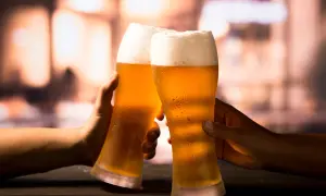 Due mani brindano con due bicchieri di birra ghiacciata, un momento di piacere che celebra la birra proprietà.
