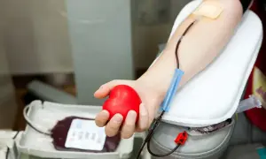 Dłoń trzymająca czerwone serce podczas oddawania krwi. Zastanawiasz się, ile dni wolnego za oddanie krwi? To ważna decyzja.