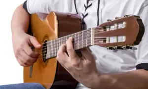 Ręce grające na gitarze klasycznej. Idealne, by zastanowić się, co zagrać na gitarze.