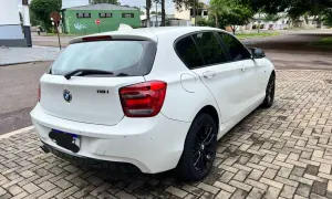 Vit vit BMW 118i står parkerad på en stenlagd uppfart. Kanske ett problem med bilen?