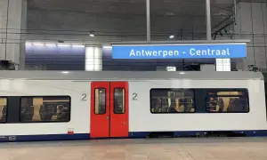 Pociągiem po Europie: biały wagon z czerwonymi drzwiami na stacji Antwerpen - Centraal. W oknach widać pasażerów.