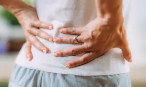 Dolore lancinante alla schiena, un vero colpo della strega non riesco a camminare. Mani che stringono i fianchi, espressione di sofferenza.