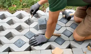 Gartenarbeit: Rasengittersteine für eine stabile Einfahrt werden verlegt. Ein Handwerker setzt die Steine präzise ein.