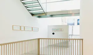Interno moderno con scale in vetro e metallo. Opere di Christian Martinelli appese alle pareti bianche.