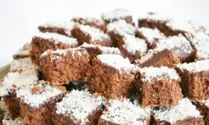 En hög med små, fyrkantiga chokladbitar, en klassisk snoddas kaka, toppade med kokosflingor.