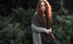 Rudowłosa dziewczyna w jesiennym otoczeniu, otulona ciepłym szalem. To piękna fotografia kreacyjna.